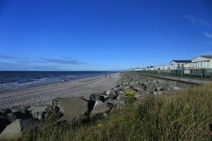 Rocky beach with distant walkers and seaside cabins