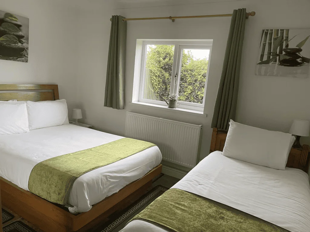 Bright dual-bed room with green accents and artwork