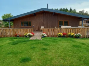 Wooden house with fenced deck and colorful flower pots