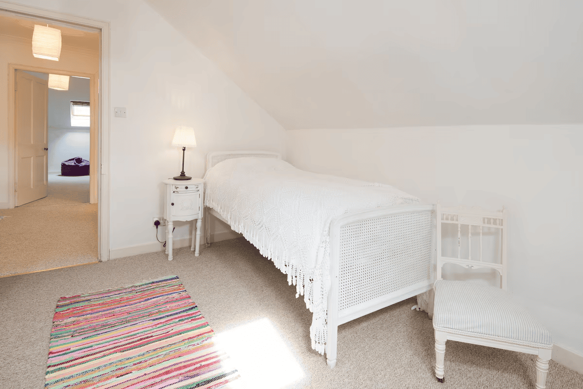 Bright cozy attic bedroom with white furniture