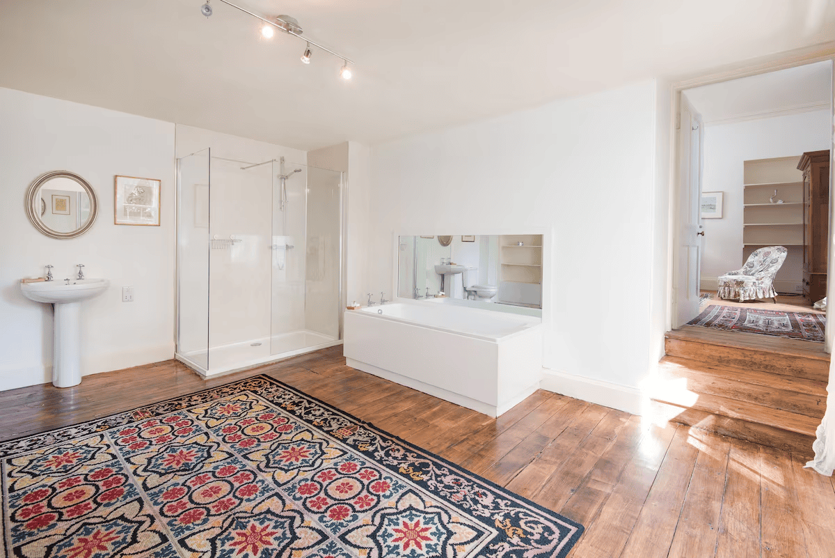 Bright spacious bathroom with tub and patterned rug