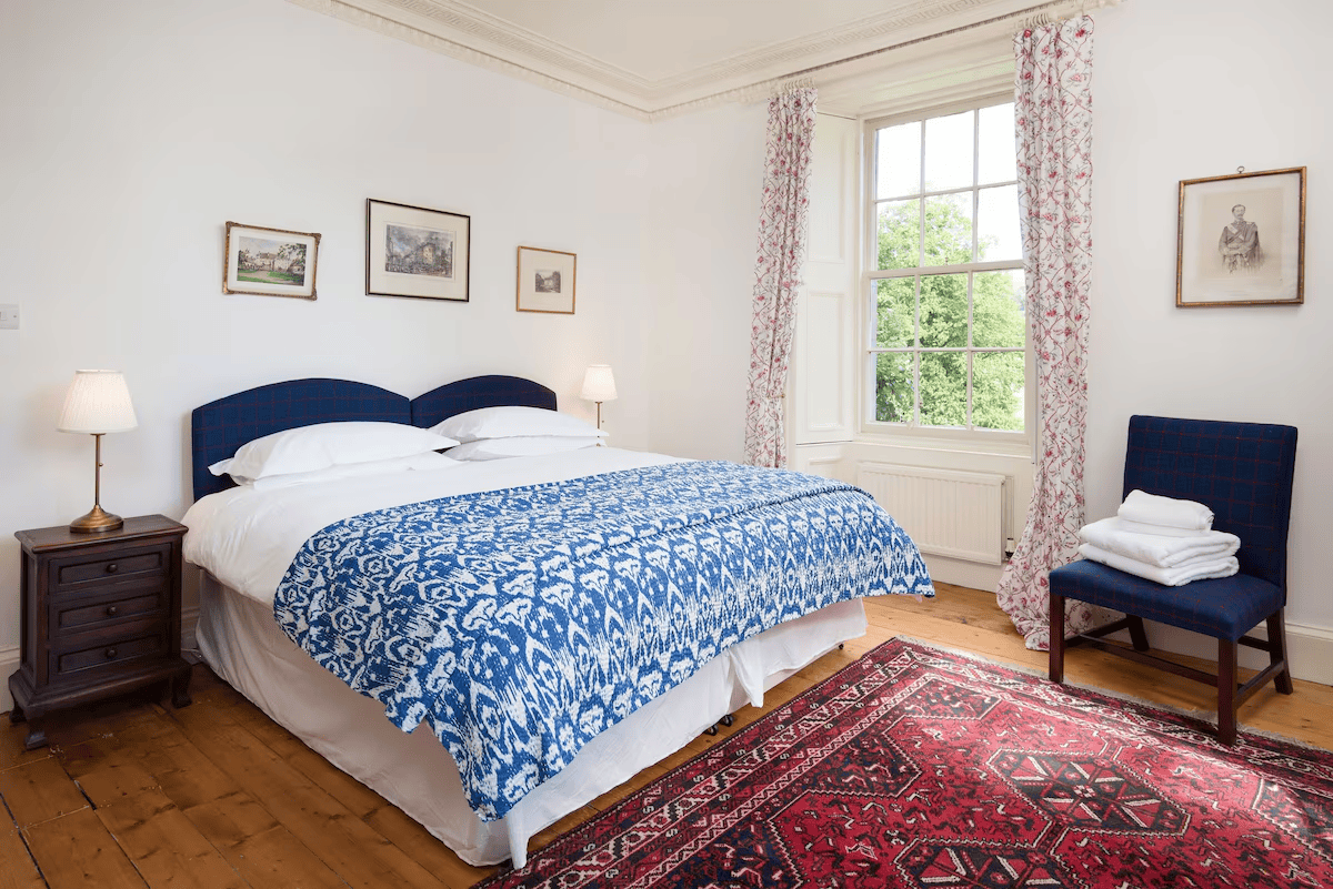 Elegant bedroom with blue bedding and red pattern rug