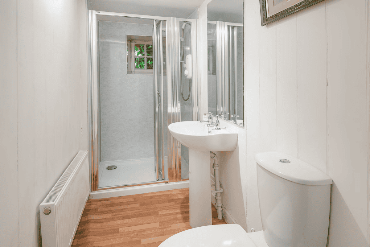 Compact bathroom with shower, sink, and white walls