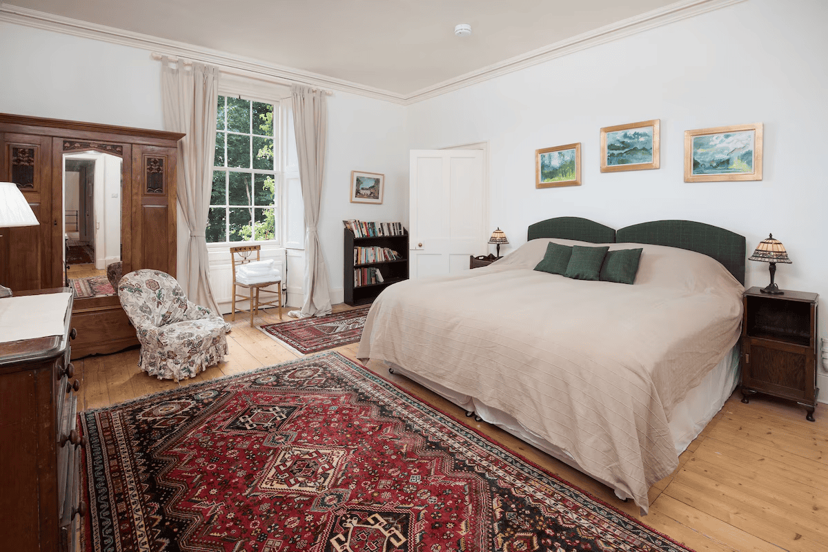 Elegant bedroom with large bed, traditional furniture, and artworks.