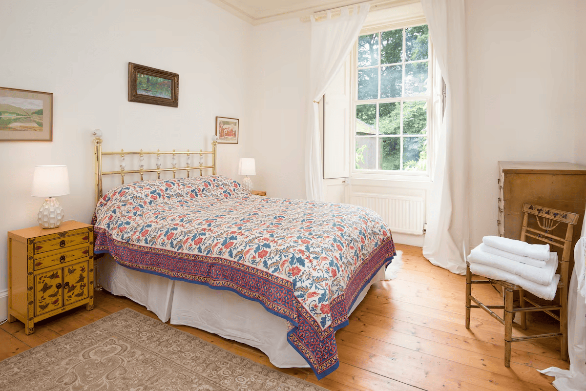 Bright bedroom with patterned bedding and garden view