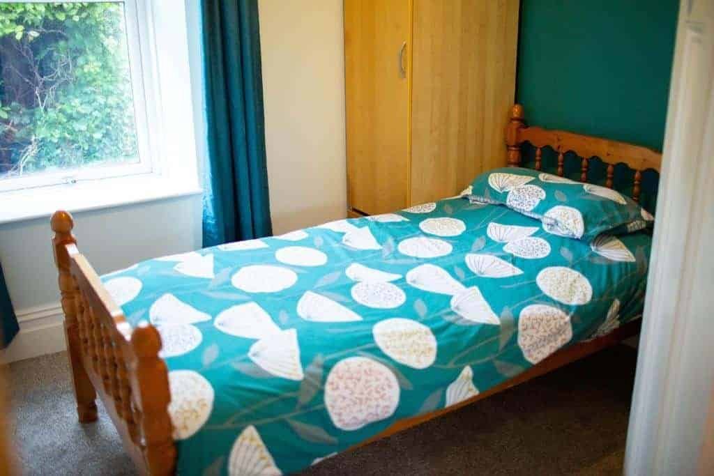 Bright bedroom with teal shell-patterned bedding and window