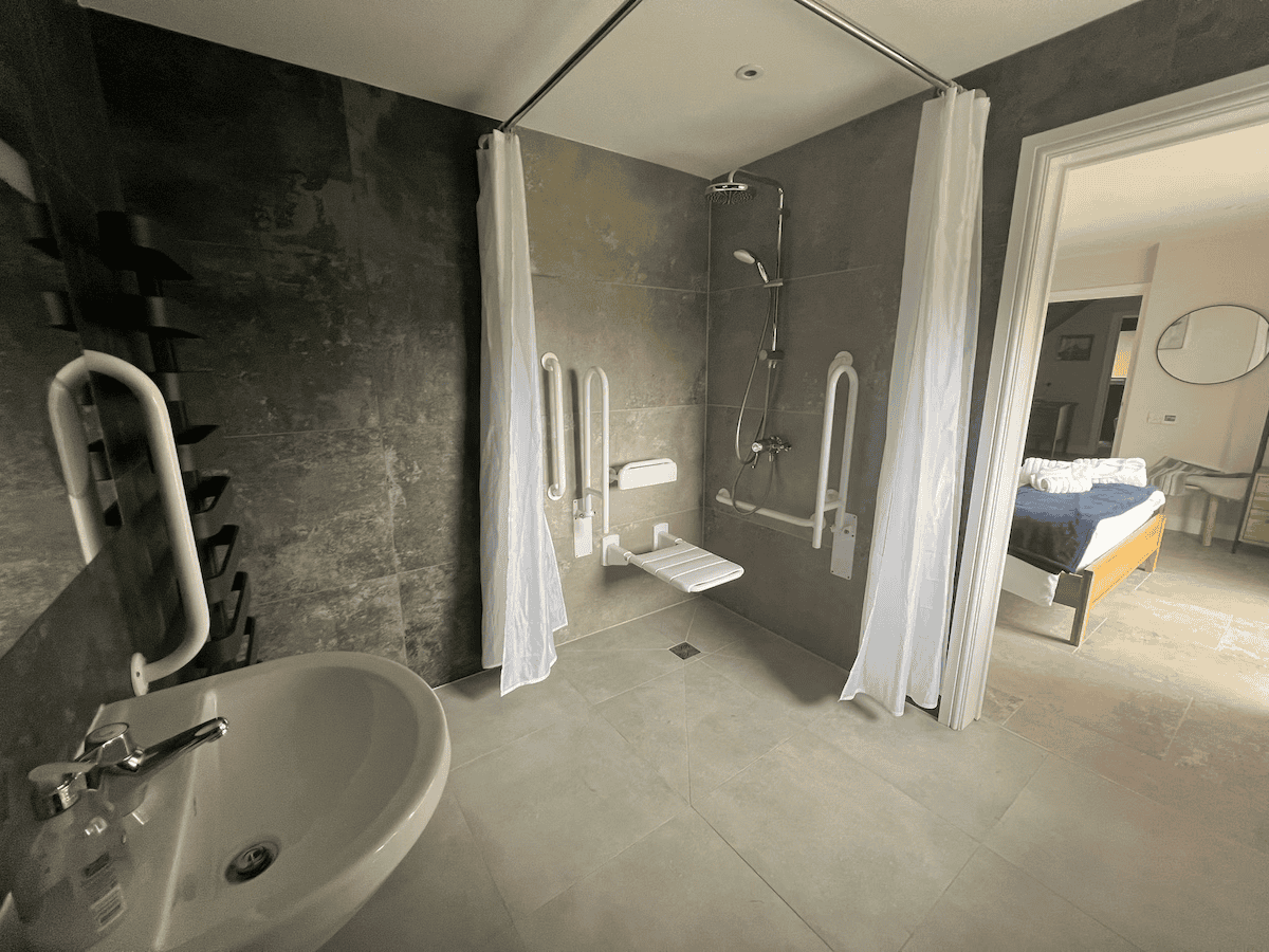 Accessible bathroom with shower and basin leading to bedroom