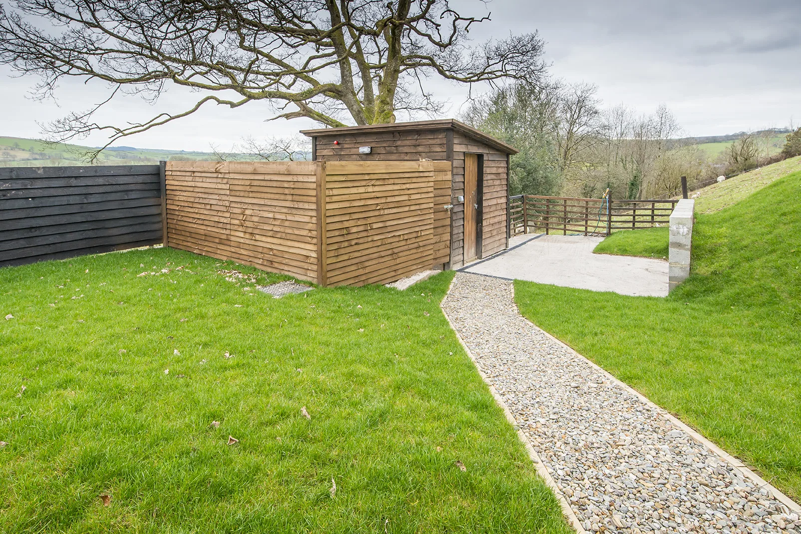 Wooden shed with gravel path in lush green landscape