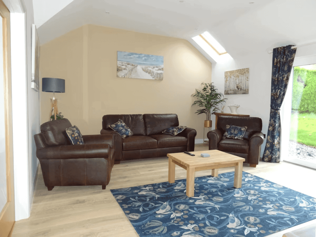 Bright living room with leather sofas and blue rug.