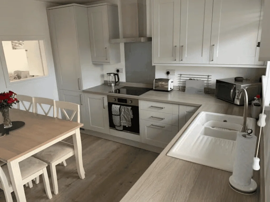 Modern white kitchen with dining area and appliances