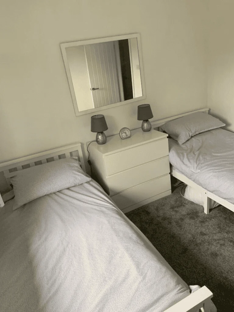 Minimalist twin bedroom with mirror and bedside lamps
