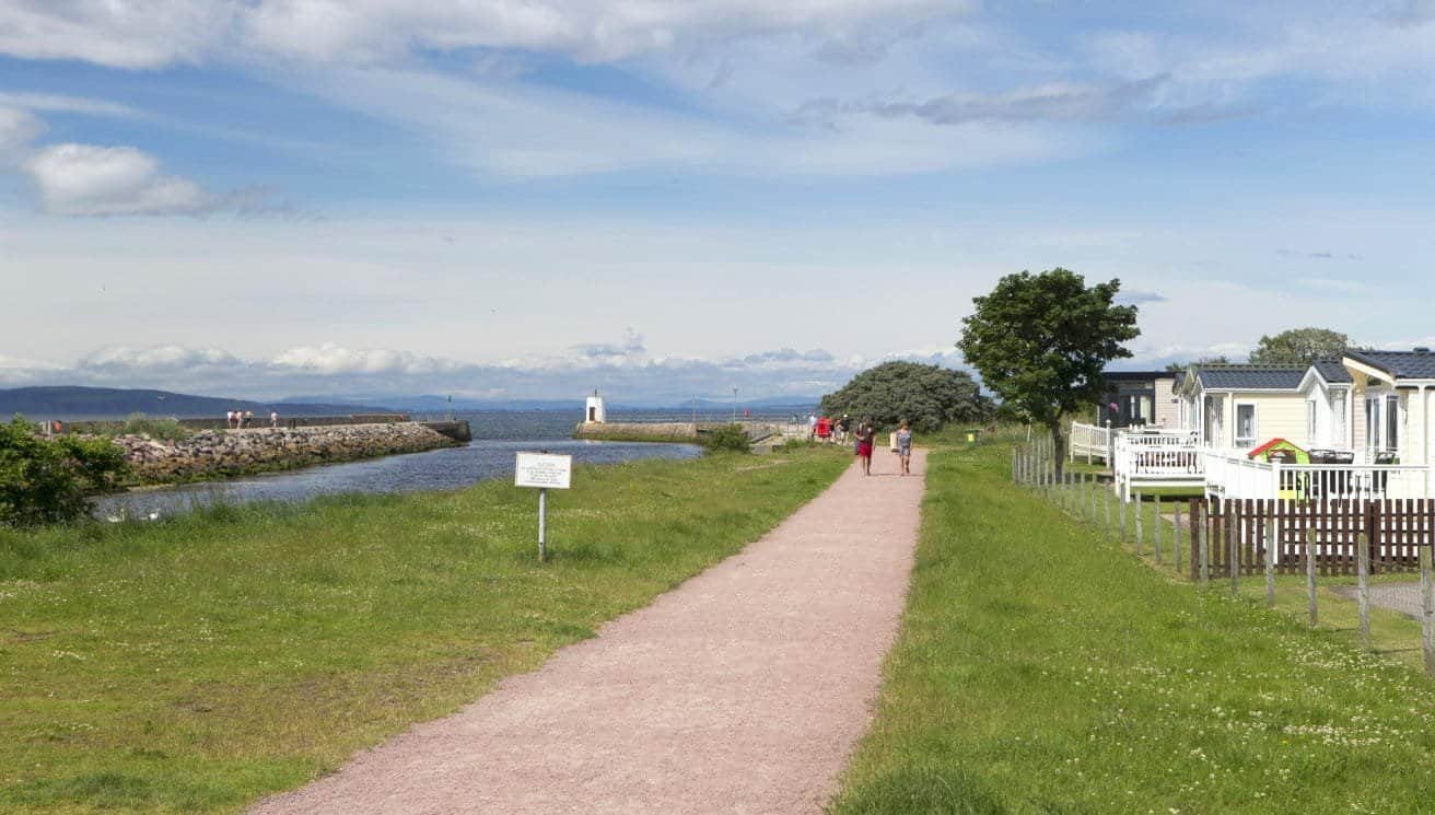 Coastal path with people, lighthouse, and mobile homes