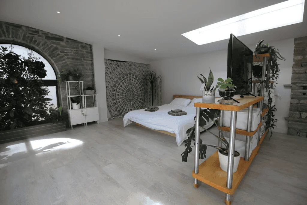 Modern bedroom with large arched window and stone wall