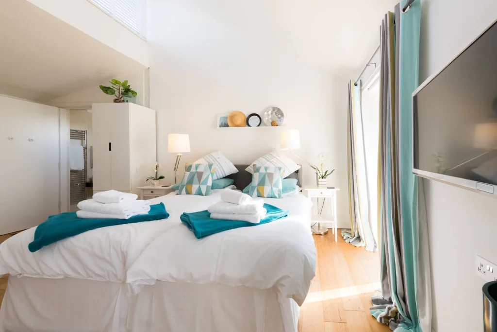 Bright modern bedroom with cozy white bedding and TV