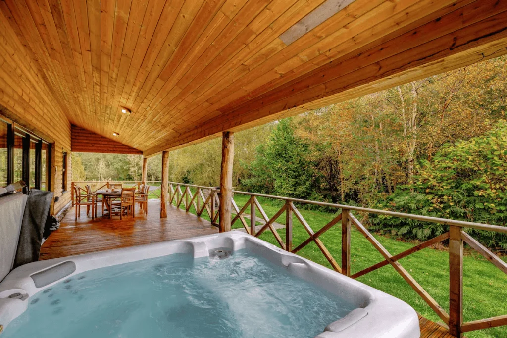 Wooden porch with hot tub and dining area overlooking forest
