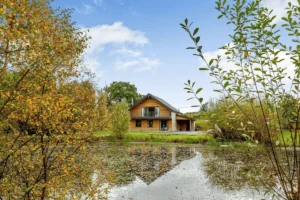 Wooden house by autumnal pond with reflective water