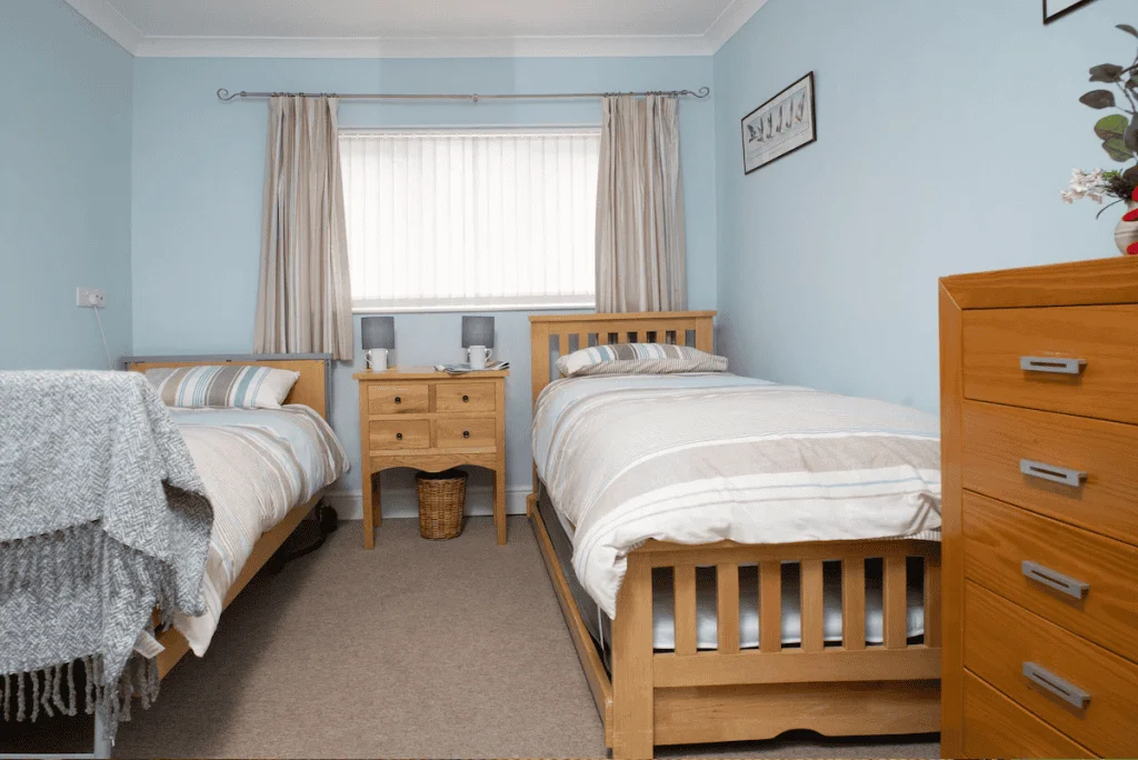 Cozy twin bedroom with light blue walls and furniture