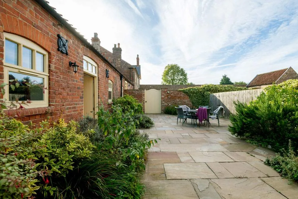 Brick house exterior with garden and patio dining set