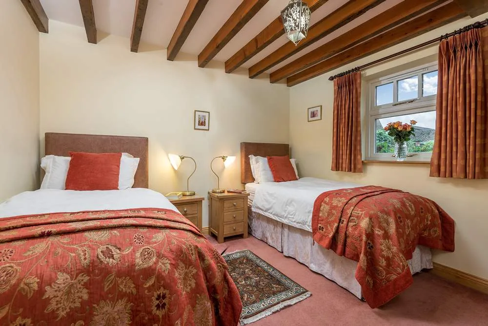 Cozy twin bedroom with exposed beams and red accents