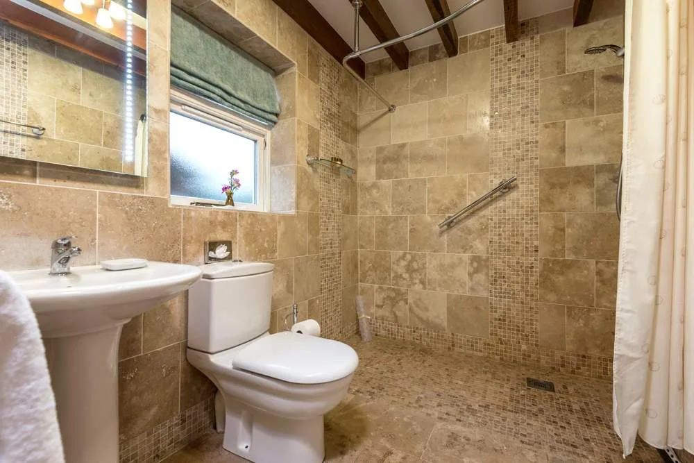 Modern beige tiled bathroom with shower and small window