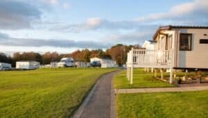 Sunlit caravan park with mobile homes and vehicles