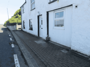 White seaside house with cobbled street on sunny day