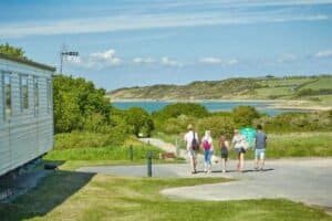 Family walking near lake by caravan on sunny day