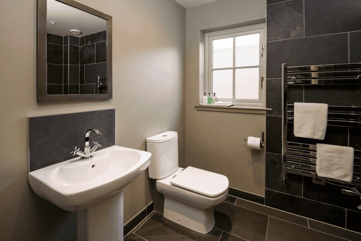 Modern bathroom with mirror, sink, toilet, and towels