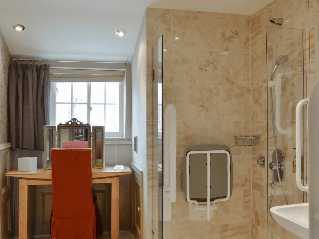 Accessible bathroom with shower chair and textured tiles.