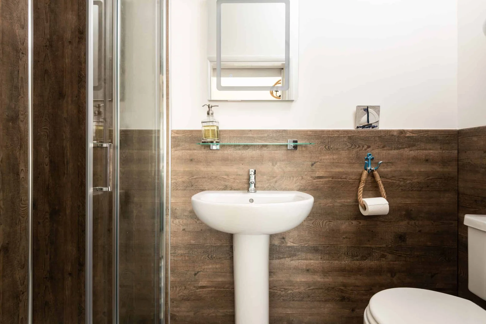 Modern bathroom with wooden walls and glass shower.