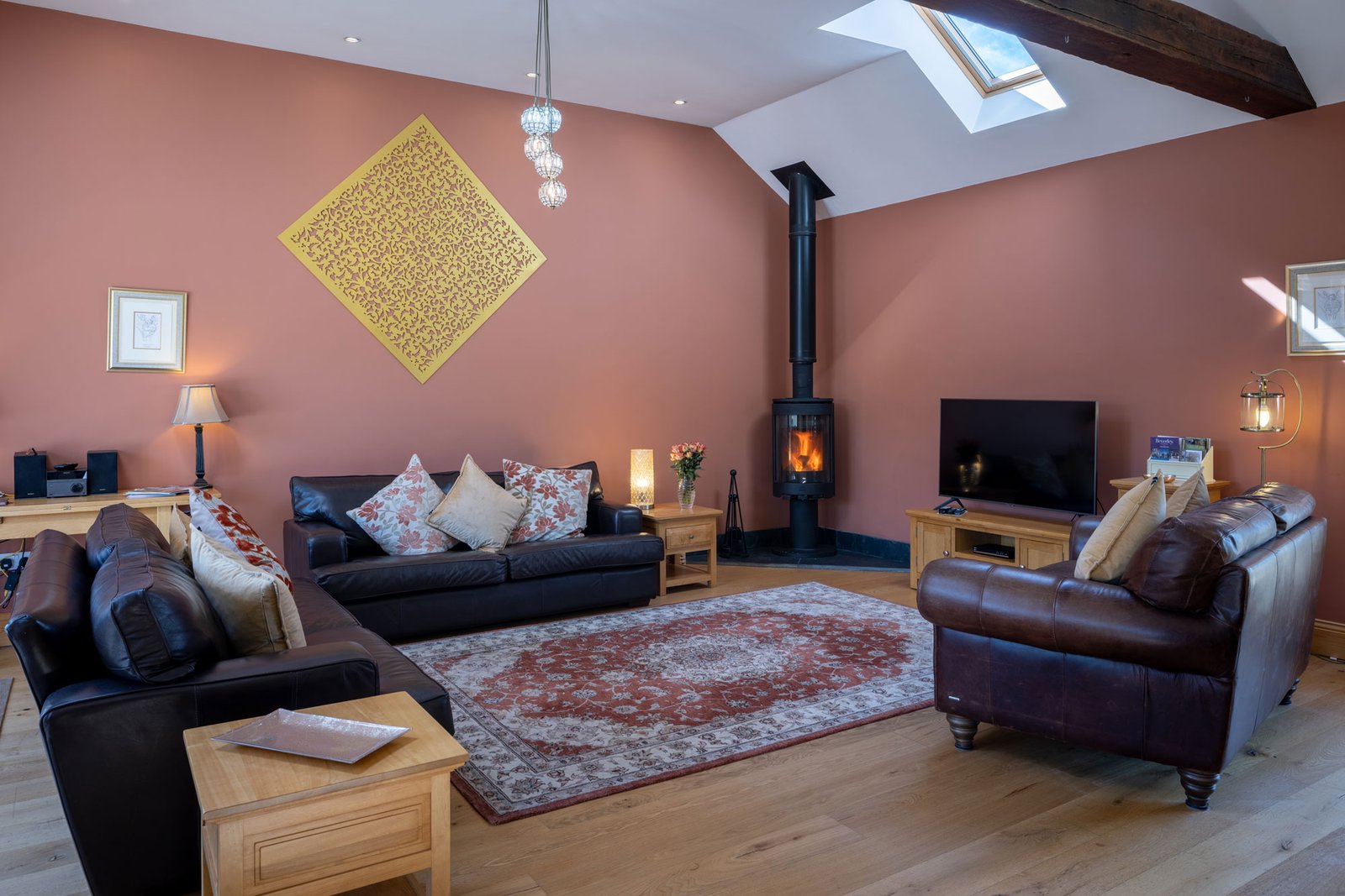 Cosy living room with leather sofas and wood stove.