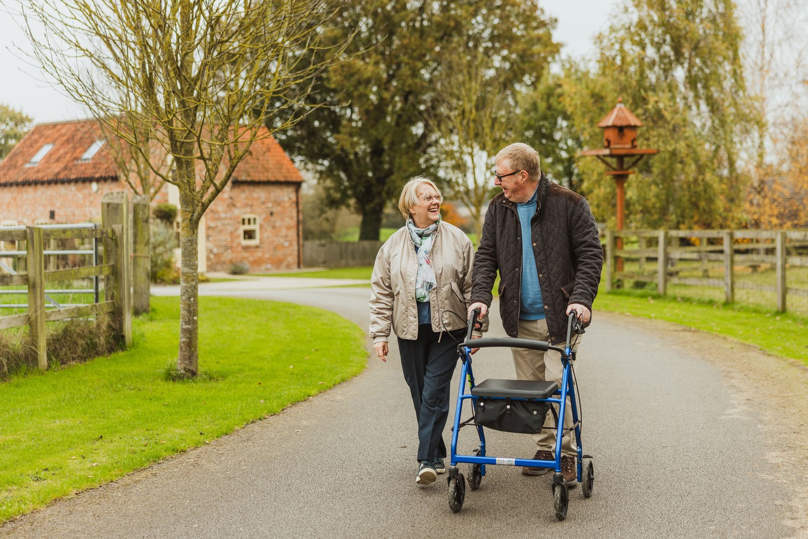 Elderly couple walking with mobility aid outdoors.