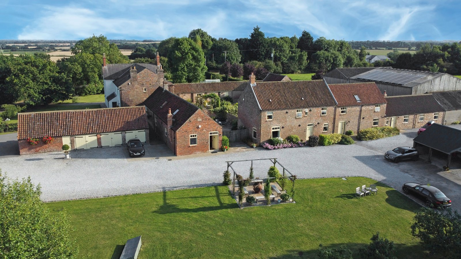 Aerial view of countryside property with garden and buildings.