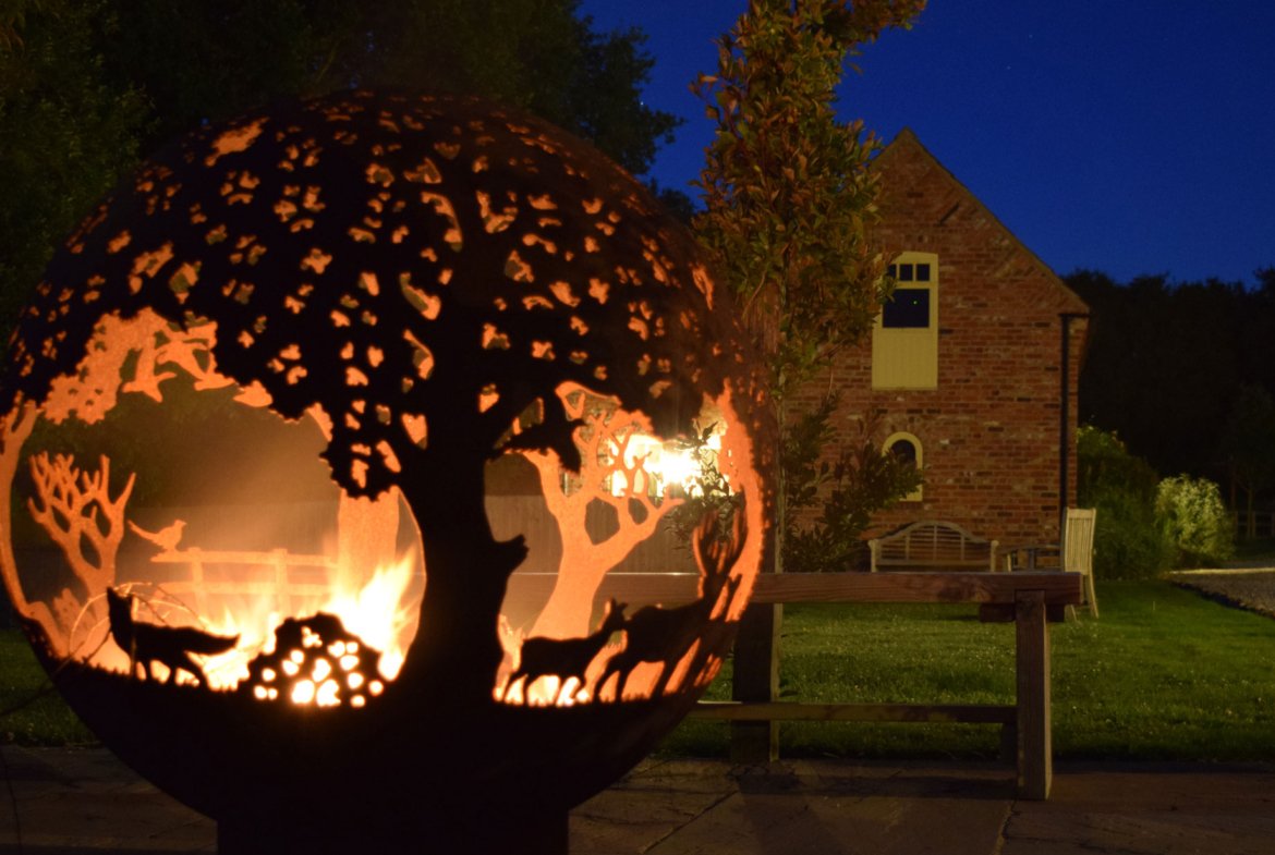 Fire pit with cut-out tree and animal design.