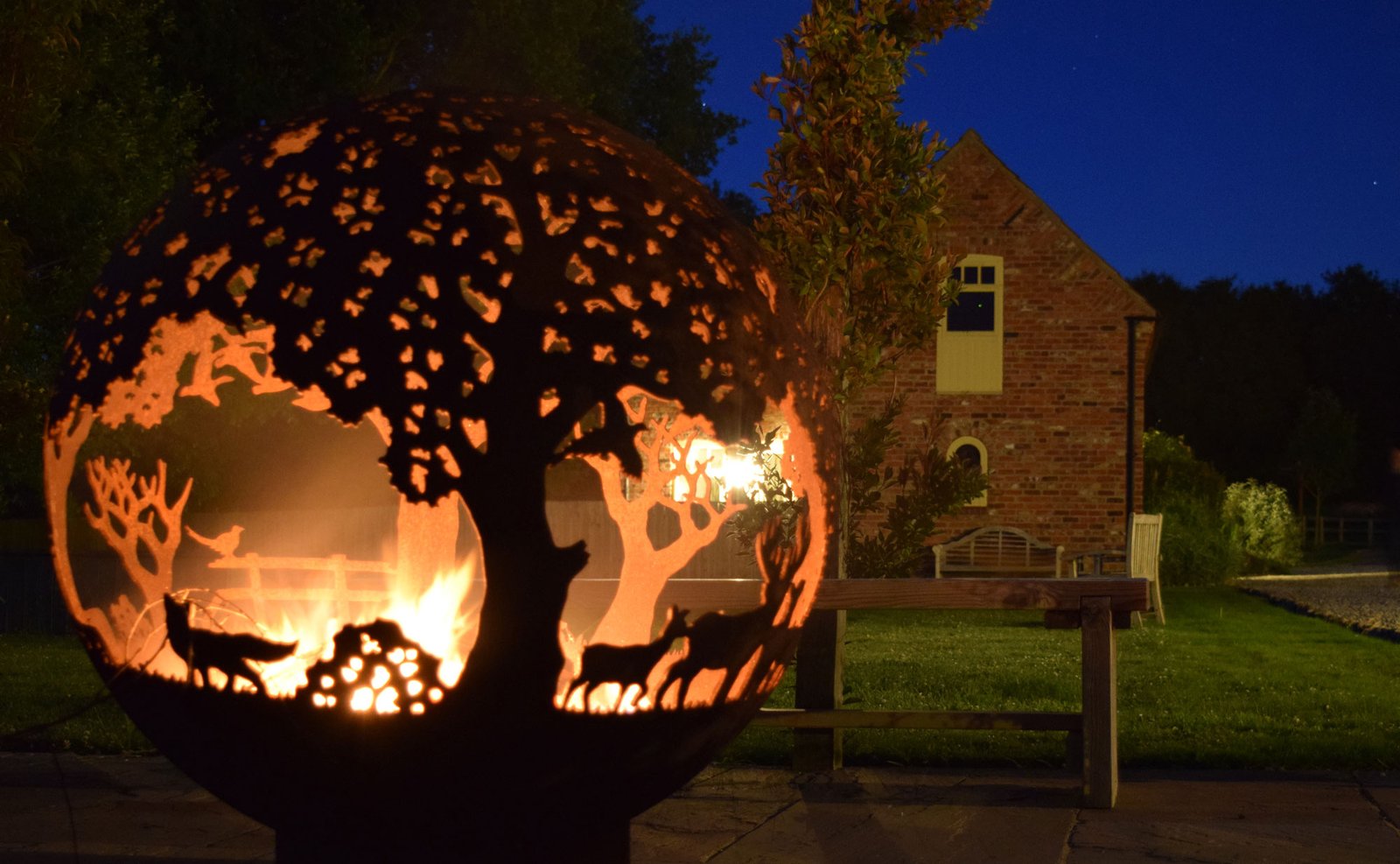Fire pit with cut-out tree and animal design.