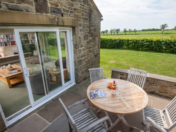 Stone patio with garden view and sliding glass door.