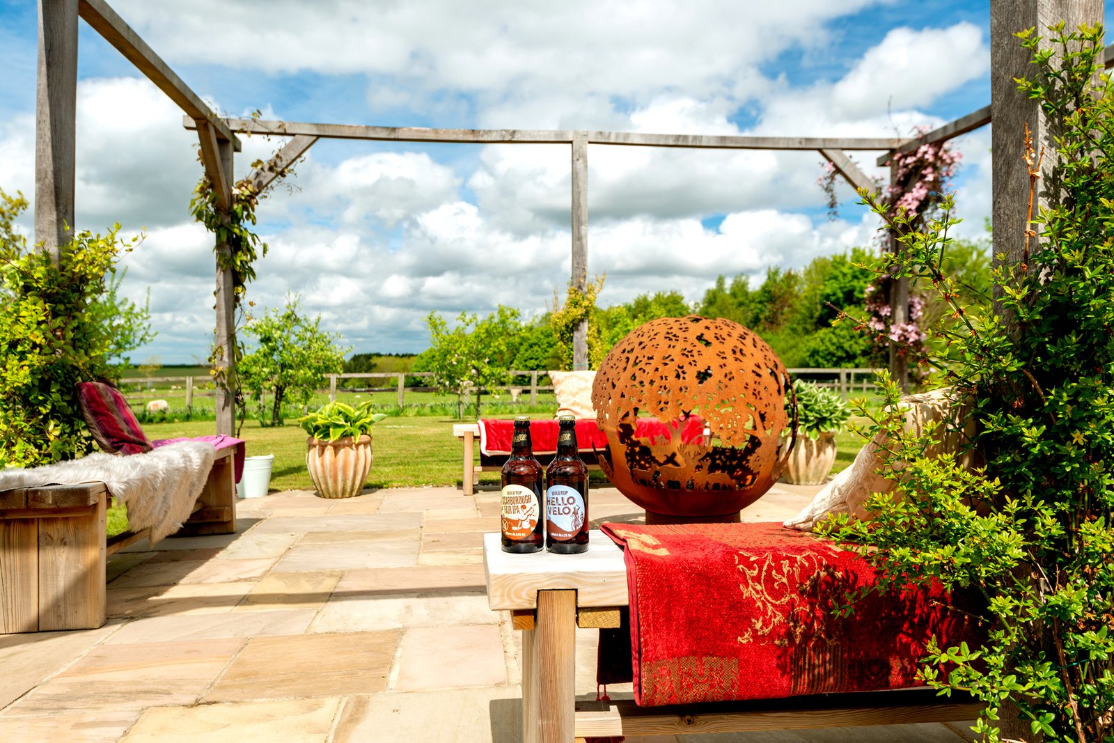 Outdoor patio with benches, decor and drinks.