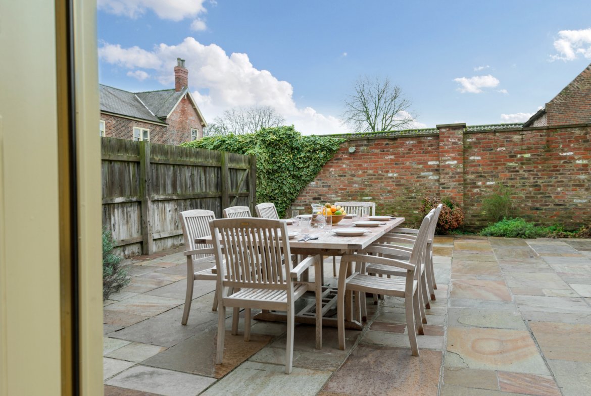 Outdoor patio dining set with brick wall background.
