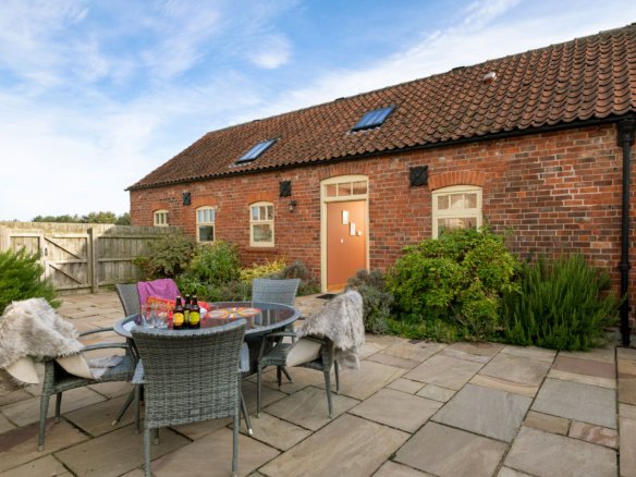 Brick cottage with patio and outdoor seating.