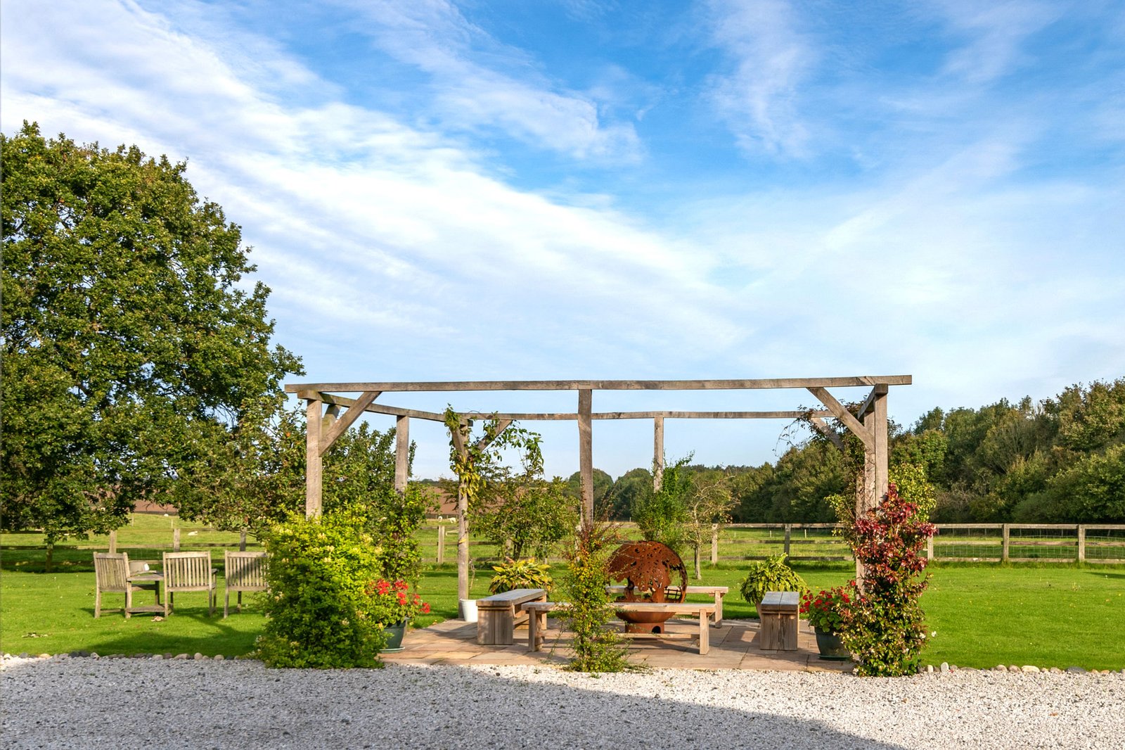 Garden pergola with benches and countryside view.