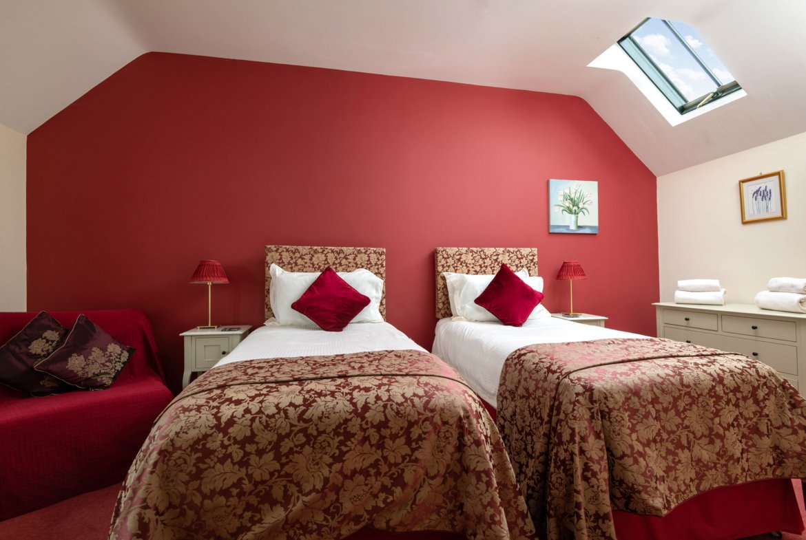 Cosy twin bedroom with red decor and skylight.