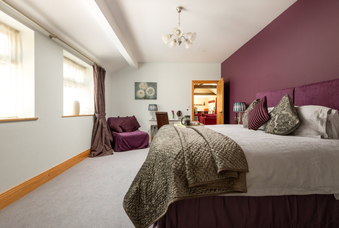 Modern bedroom with purple accents and large bed.