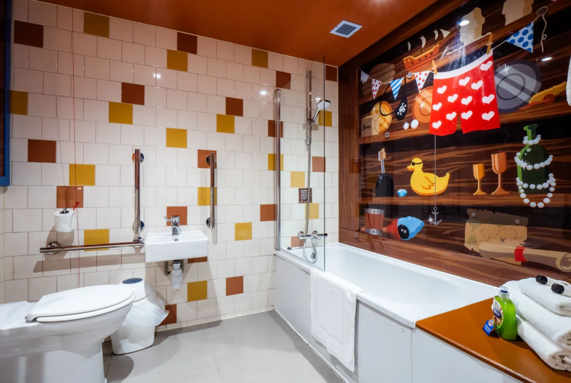 Colourful accessible bathroom with mural and bathtub.