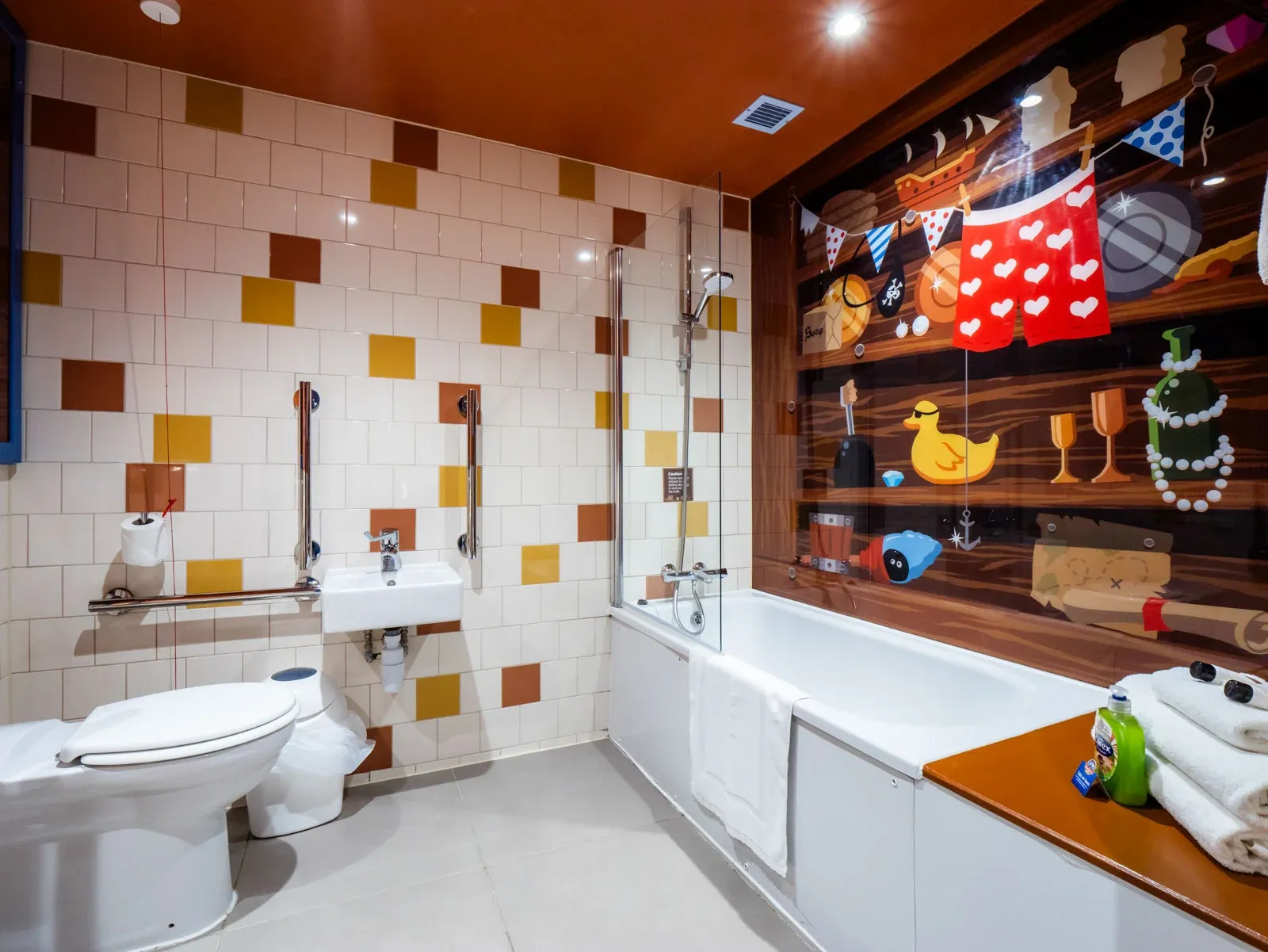 Colourful accessible bathroom with mural and bathtub.