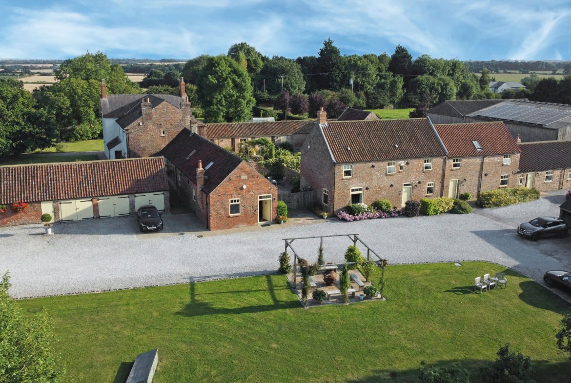 Aerial view of countryside brick cottages and gardens.