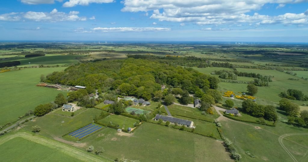 Aerial view of countryside estate with fields and trees.