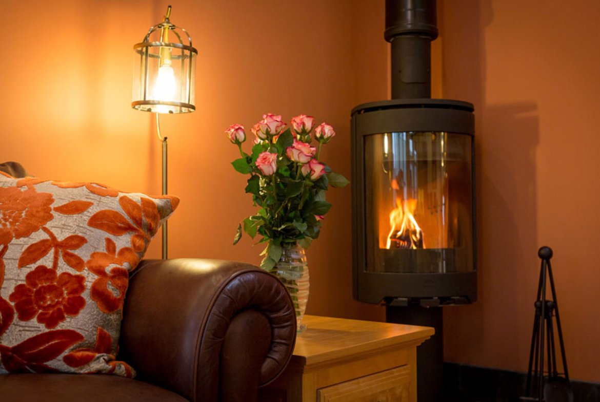 Cosy room with fireplace, flowers, and lamp.