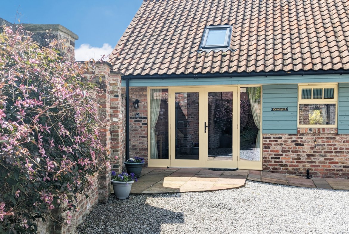 Cottage entrance with flowers and wooden door.