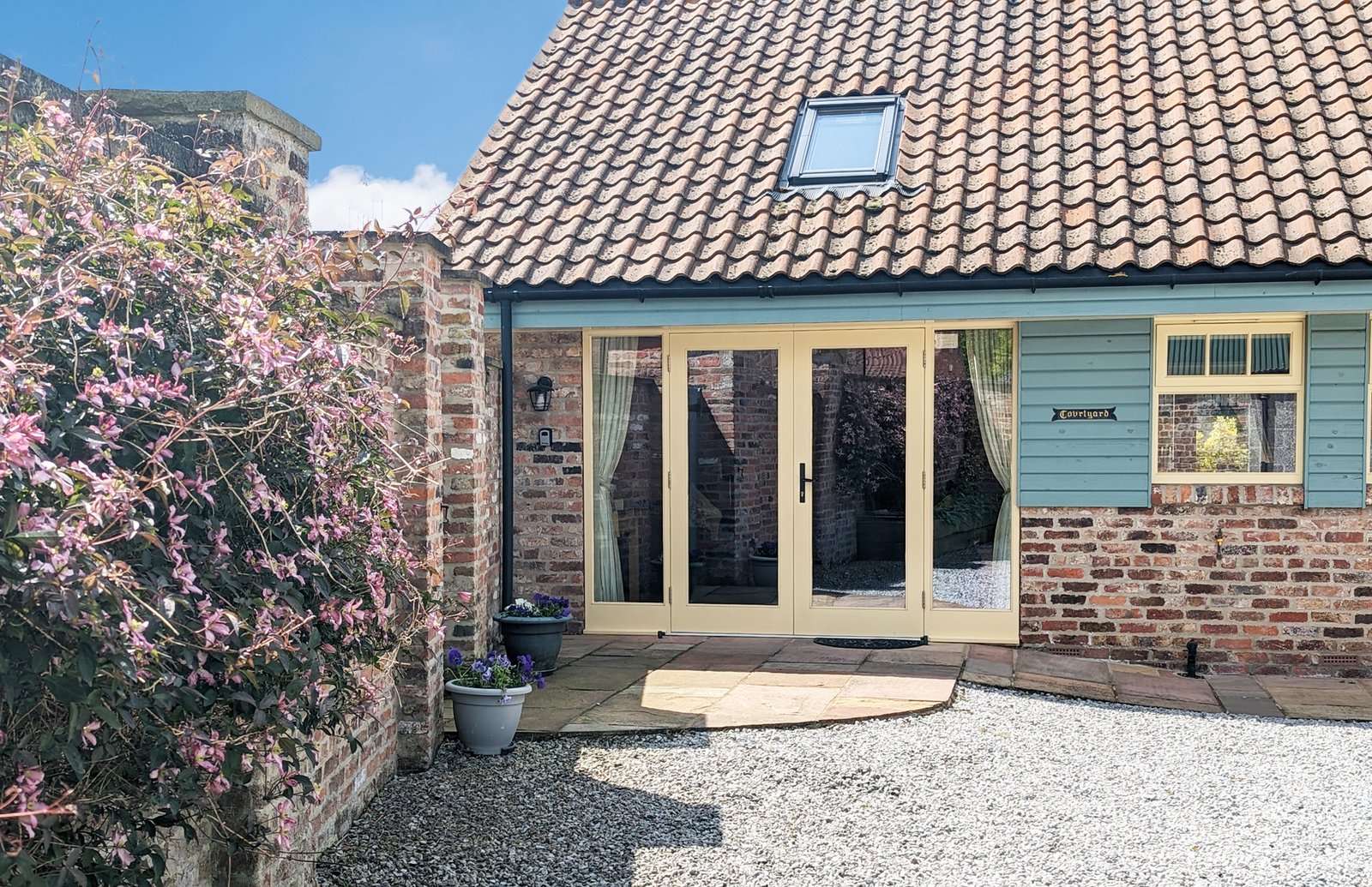 Cottage entrance with flowers and wooden door.