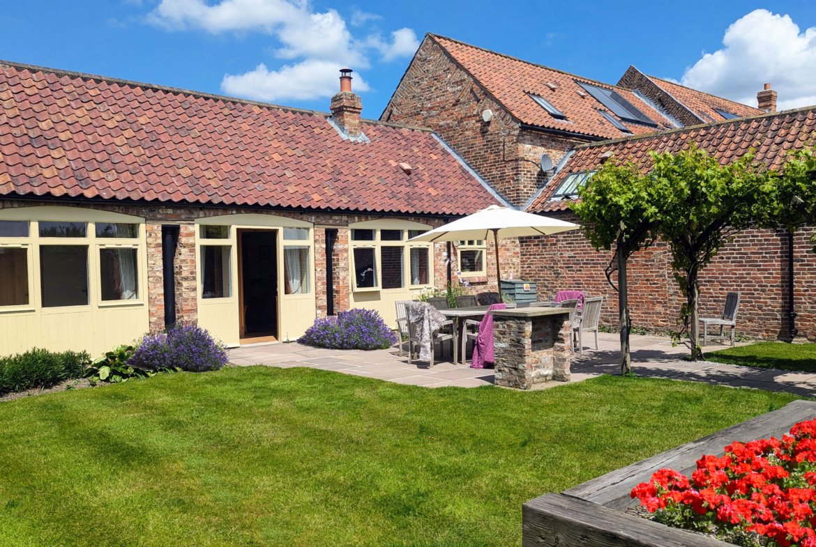 Charming cottage courtyard with garden and patio furniture.